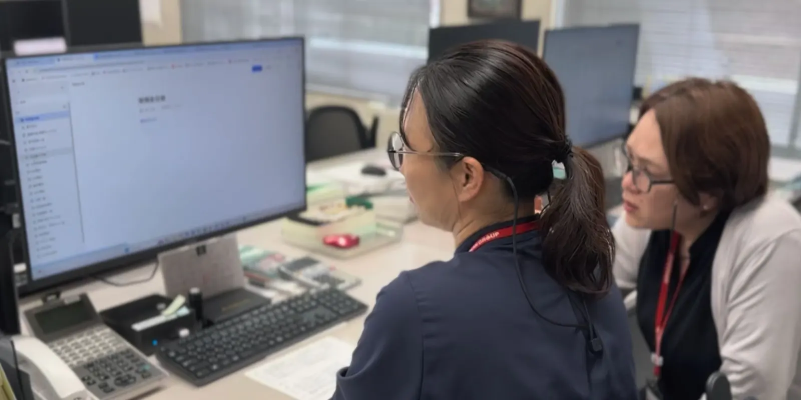 事務所でLarkの画面を見ながら業務を進めるスタッフ