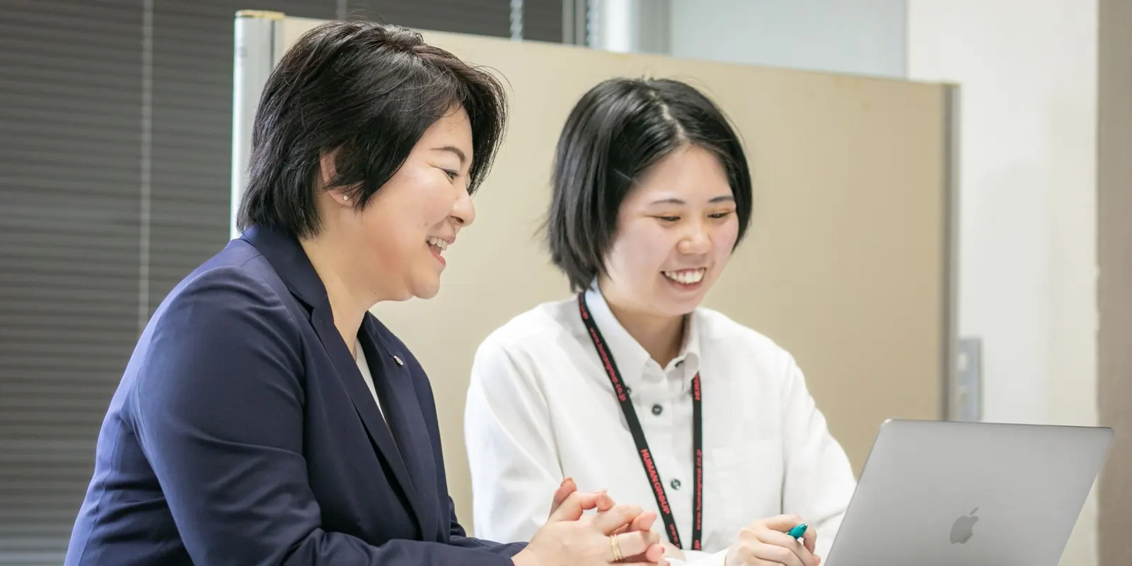 ノートパソコンを見ながら打ち合わせをする社員